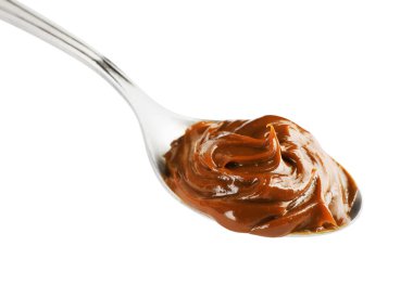 Beyaz üzerine izole edilmiş kaynamış konsantre sütle dolu kaşık.