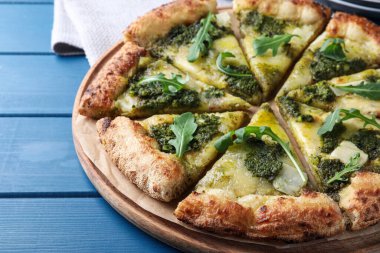 Pesto, peynir ve roka ile nefis pizza mavi ahşap masada, yakın plan.