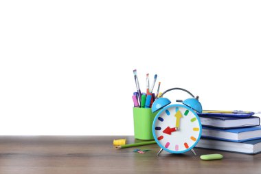 Açık mavi alarm saati ve ahşap masada beyaz arka plana karşı farklı kırtasiye malzemesi, yazı için yer. Okul zamanı.