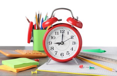 Kırmızı alarm saati ve beyaz arka plandaki ahşap masa üzerindeki farklı kırtasiye malzemeleri. Okul zamanı.