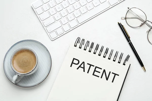 笔记本 印有Patent 一杯咖啡 白色桌子上的钢笔和眼镜 — 图库照片