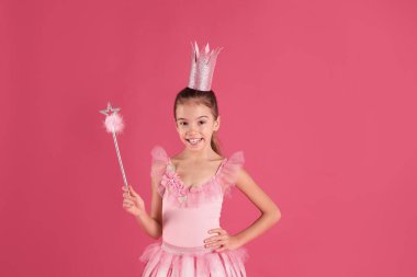 Pembe arka planda tacı ve sihirli değneği olan peri elbiseli tatlı bir kız. Küçük prenses.
