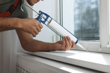 İnşaat işçisi. Caulk kapalı, pencereyi kapatıyor.
