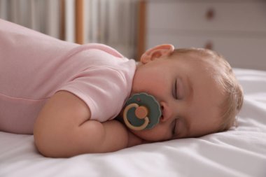 Emziği olan, evde yatağında uyuyan sevimli bir bebek.