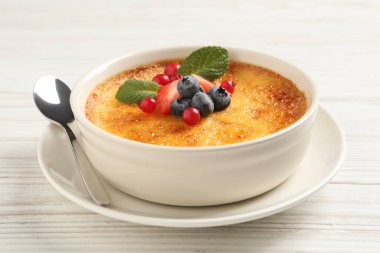 Beyaz ahşap masada taze böğürtlenli leziz creme brulee, yakın plan.