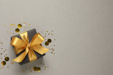 Gri arka planda güzel bir hediye kutusu ve konfeti. Metin için boşluk