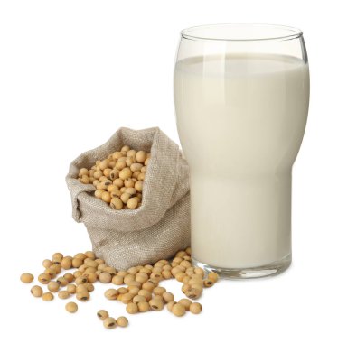 Bir bardak taze soya sütü ve beyaz arka planda fasulye torbası.