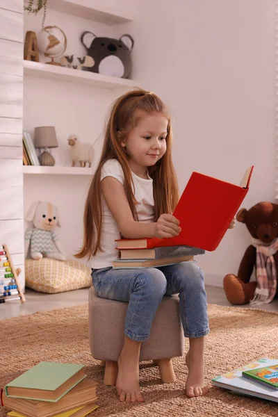 Χαριτωμένο Κοριτσάκι Διαβάζει Βιβλίο Για Pouf Στο Δωμάτιο — Φωτογραφία Αρχείου