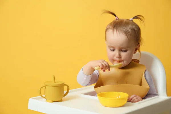 Cute Little Baby Wearing Bib While Eating Yellow Background — Stock Photo, Image