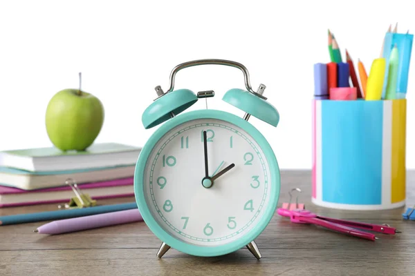 蓝绿色闹钟 木制桌子上有不同的文具 背景为白色 上课时间 — 图库照片