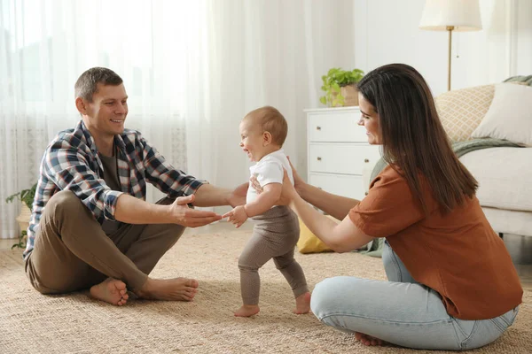 Parents Supporting Baby Daughter While She Learning Walk Home Stock Image