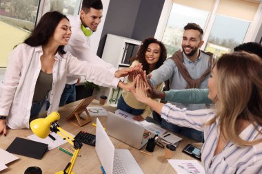 Çalışanlardan oluşan bir ekip ofiste el ele tutuşuyor. Başlangıç projesi