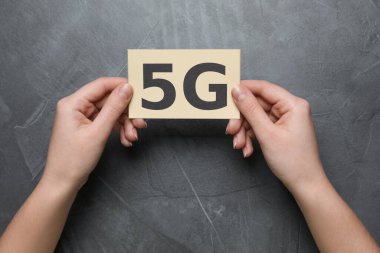 5G teknolojisi, internet konsepti. Gri masadaki kartı olan kadın, üst manzara.