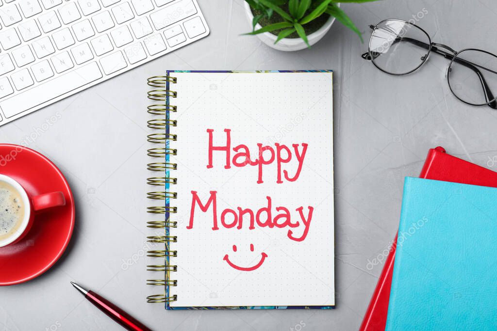 Message Happy Monday written in notebook, office stationery and cup of coffee on light desk, flat lay