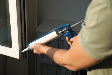 İnşaat işçisi. Caulk kapalı, pencereyi kapatıyor.