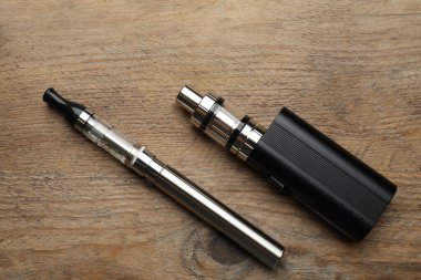 Tahta masada farklı elektronik sigaralar, düz yatış. Sigara alternatifi