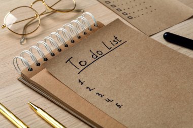 Tahta masa üzerinde doldurulmamış yapılacaklar listesi olan not defteri ve sayfa, kapat