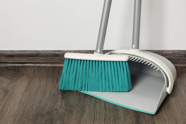 Ahşap zeminde faraş olan plastik süpürge.