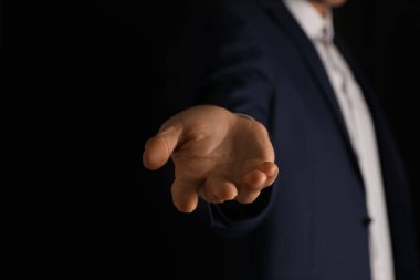 Siyah arka planda bir şey tutan adam, yakın plan.