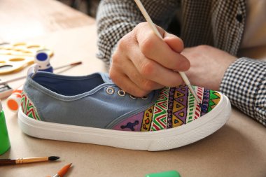 Masada spor ayakkabısı boyayan bir adam, yakın plan. Özelleştirilmiş ayakkabılar