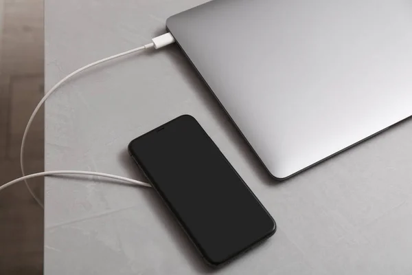 Смартфон Бездротовим Зарядним Пристроєм Підключеним Ноутбука Світло Сірому Столі Вид — стокове фото