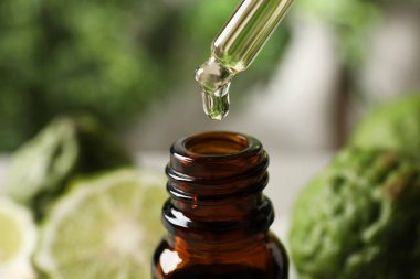 Bergamot yağı cam şişeye damlıyor. Arka planda bulanıklık var. Yakın plan.