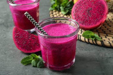 Lezzetli pitahaya smoothie, meyveler ve gri masada taze nane.