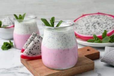 Lezzetli pitahaya smoothie, meyveler ve beyaz mermer masada taze nane.