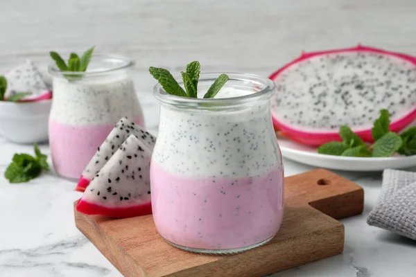 Lezzetli pitahaya smoothie, meyveler ve beyaz mermer masada taze nane.