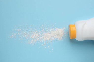 Açık mavi arka planda şişe ve toz alma tozu, üst manzara. Bebek kozmetik ürünü