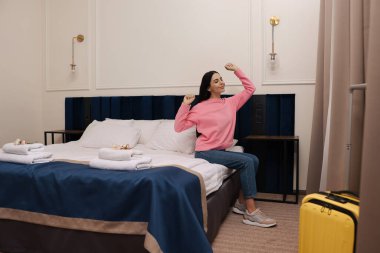 Güzel genç bir kadın otel odasında yatakta dinleniyor.
