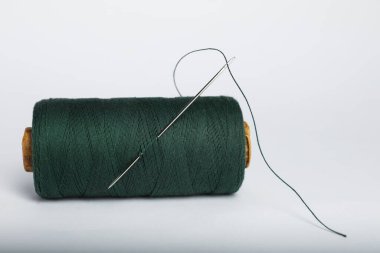 Beyaz zemin üzerinde iğne olan yeşil dikiş ipliği