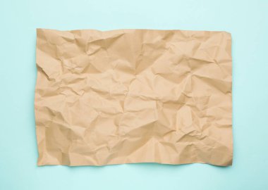 Açık mavi zemin üzerinde buruşuk kahverengi kağıt yaprağı, üst görünüm