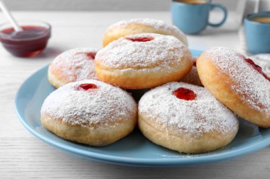 Reçelli ve pudra şekerli leziz çörekler beyaz masada, yakın plan.