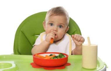 Beyaz arka planda yemek yerken önlük takan şirin bir bebek.