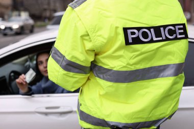 Kadın polis memuruna araba camından rüşvet veriyor, yakın plan.