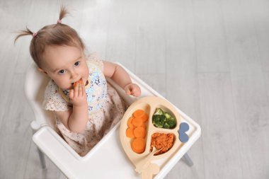 İçeride, yüksek sandalyede yemek yiyen şirin bir bebek. Metin için boşluk