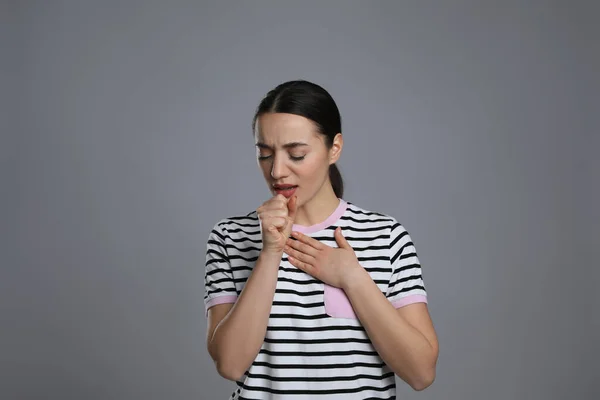 灰色の背景で咳をする若い女性 風邪の症状 — ストック写真