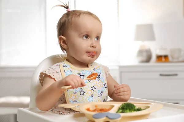 かわいい赤ちゃんは家で高い椅子で食べ物を食べる — ストック写真