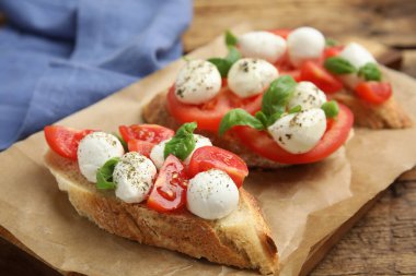 Mozzarella 'lı lezzetli sandviçler, taze domates ve parşömen üzerine fesleğen.