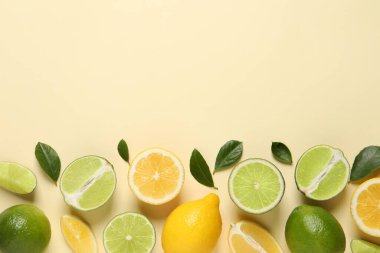 Taze limon, limon ve yeşil yapraklar bej arka planda, düz yerde. Metin için boşluk