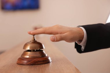 Oteldeki ahşap resepsiyonda servis zilini çalan adam, yakın plan.