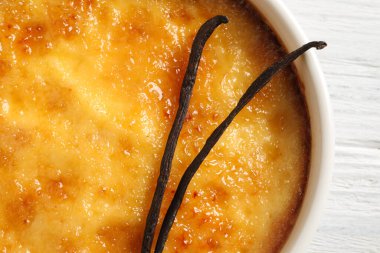 Lezzetli creme brulee ve vanilyalı çubuklar beyaz ahşap masa, üst manzara