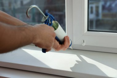Caulk ile pencereyi kapatan adam, yakın plan.