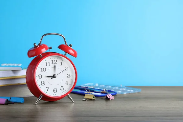 Red Alarm Clock Different Stationery Wooden Table Light Blue Background — Stock Photo, Image