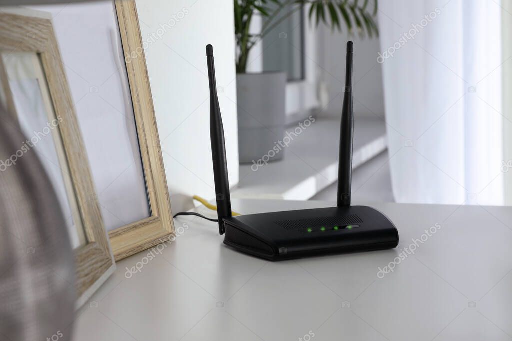 Modern Wi-Fi router on white table in room