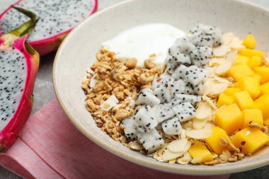 Bir kase granola, pitahaya, mango ve yoğurt, yakın plan.