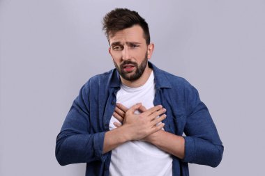 Gri arka planda soğuktan muzdarip bir adam