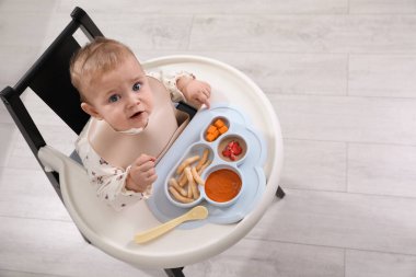 İçeride, yüksek sandalyede yemek yiyen şirin bir bebek. Metin için boşluk