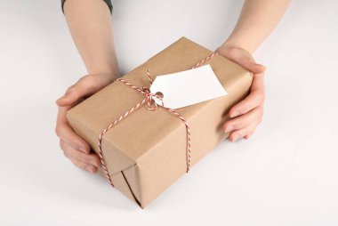 Beyaz arkaplanda etiketi olan bir paket tutan kadın, yakın plan.